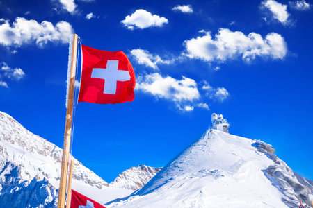 Swiss flag on Jungfraujoch peak and Sphinx observatory view, Berner Oberland region of Switzerlandの写真素材