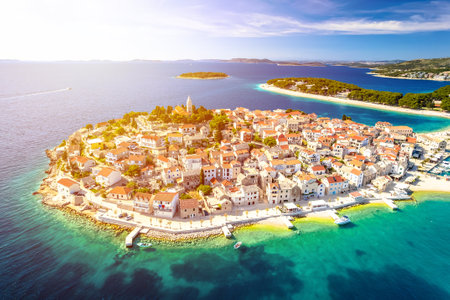 Scenic town and beaches of Primosten aerial panoramic sun haze view, turquoise archipelago and historic architecture of Croatiaの写真素材