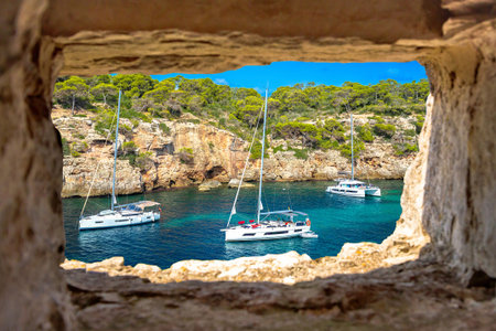 Secret turquoise beach yachting and sailing view through stone window, Island of Mallorca. Cala Pi beach. Balearic islands of Spainの写真素材