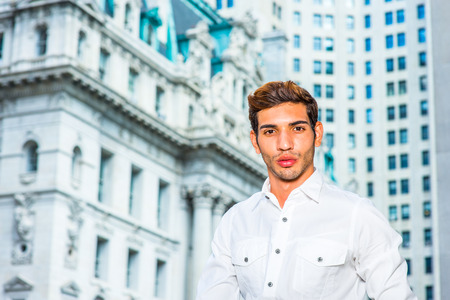 Portrait of Young Businessman. Wearing a white shirt, a young college student is standing in the front of business district, confidently looking forward.の写真素材