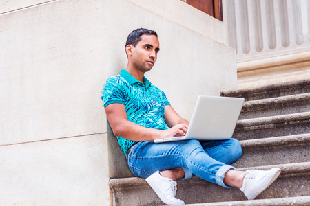 Young Hispanic American college student studying in New York, wearing green patterned Polo shirt,...
