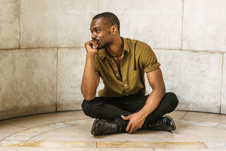 Young African American Man wearing green short sleeve shirt, black pants, leather shoes. legs...