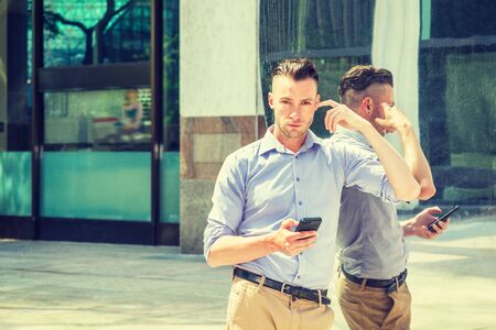 Young handsome man texting on cell phone outside in New York City, wearing long sleeve, light purple...