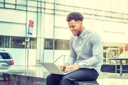 Young Happy Mix-Race American Man enjoying working outside in New York City, wearing light gray long...