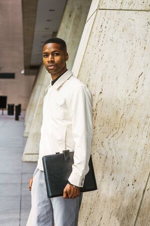 Young African American Businessman working in New York. Young black man wearing light color jacket,...