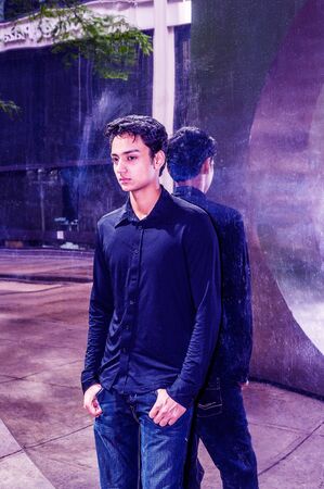 Lonely East Indian American teenager thinking outside in New York City, wearing black long sleeve...