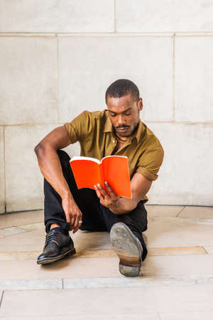 Young African American Male College Student with beard studying in New York City, wearing green...