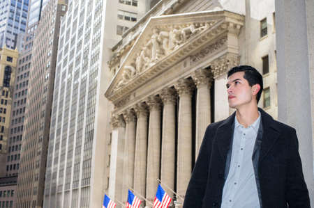 A young professional is standing outside of a business district and looking forwardの写真素材