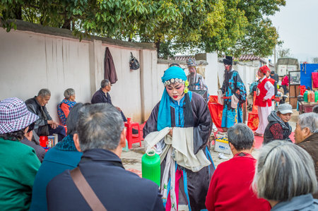 ANQING, CHINA - March 23: Street artists perform a traditional opera on the street on March 23, 2014. One actress serves hot drinking water to spectators during a show break.のeditorial素材