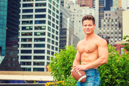 American City Boy. Manâs Beauty. Shirtless, half naked, waring jeans, a young, strong, sexy guy, holding football, standing outside business district in New York, enjoying outdoor activity after work.の写真素材