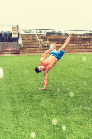 Man Playing in Rain, foggy, wet, grainy feel. Shirtless, half naked, wearing blue shorts, one arm...