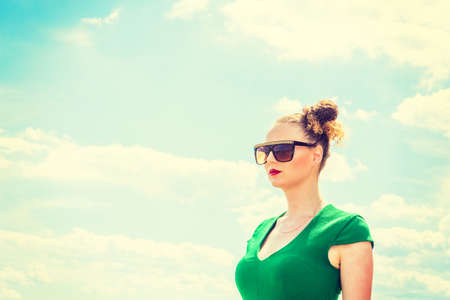 Pretty, Sexy American Lady under sunny sky in hot summer, wearing sunglasses, dressing in green,...