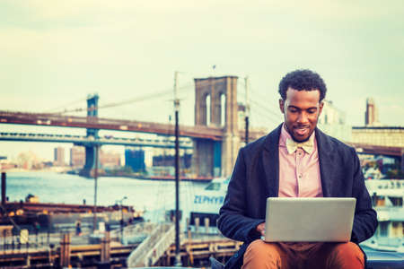 African American Businessman traveling, working in New York, wearing woolen overcoat, pink shirt,...