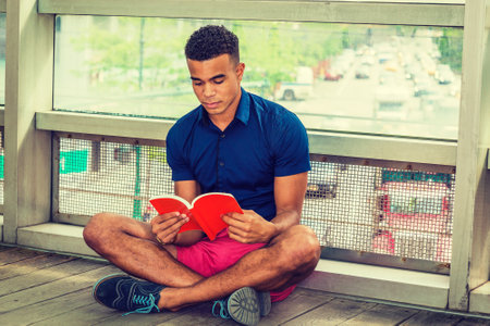 City Boy. Way to Success. I Love Reading. African American college student sitting cross legged on...