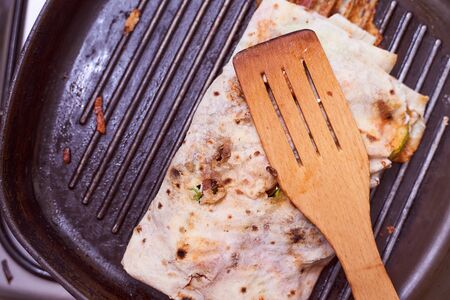 shaverma in homemade lacais rests on a grilled wooden spoon Closeup effect