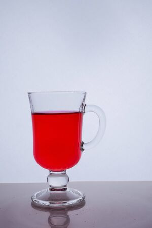 red liquid into a glass on a white background light effect Very high quality photoの写真素材