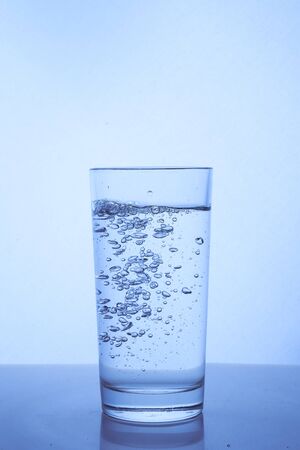 fresh clean water is poured from a bottle into a glass cup. Light background.. Hight quality photoの写真素材