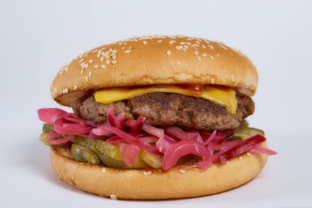 Juicy burger with onion rings, jalapeno pepper, cucumbers, lettuce, cheese on a white background. High quality photoの写真素材