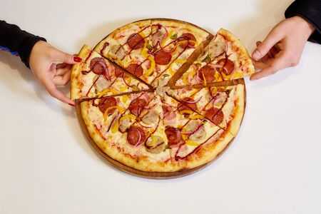 Women's and men's hands take one piece of pizza. White Background. High quality photo