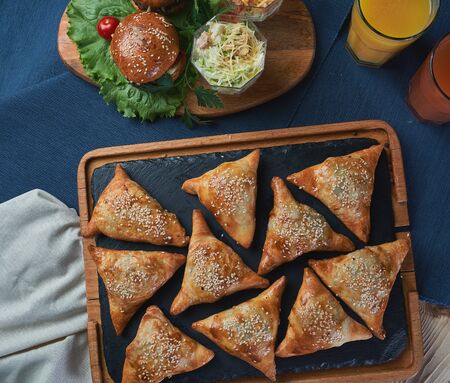 Uzbek dish - mini samosa with sesame seeds on a stone slab. Light effects . High quality photoの写真素材