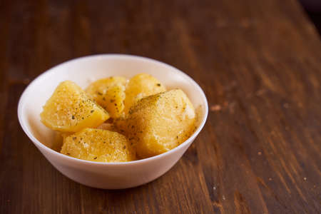 Boiled potatoes with mslom seasonings in a plate on a brown background. High quality photoの写真素材