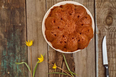 Homemade cupcake with chocolate filling inside on a wooden table with a Yellow Woodland tulips, Wild tulips on a wooden background. Close-up.. High quality photoの写真素材