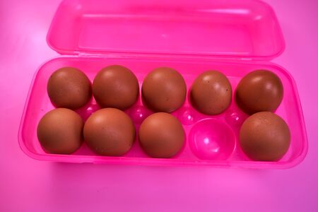 chicken eggs with plastic box on a pink background. High quality photo