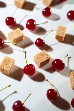 Group of cherry on a white background with cubes of reed sugar and shadows. Close-up. Top view. High quality photoの写真素材