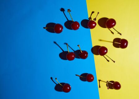 cherry on blue and yellow background with shadows effect. High quality photoの写真素材