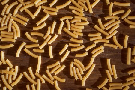 Yellow pasta lies on a brown table. High quality photoの写真素材