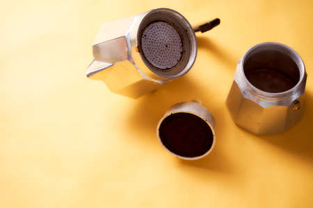 Open geyser coffee maker with fresh coffee on a yellow background