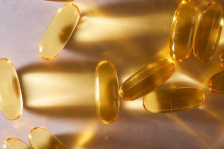 Golden Capsules Omega 3 Vitamins Lie On White Background. High quality photoの写真素材