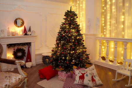 New Years interior with Christmas tree, fireplace, pillows. Very beautiful evening photo for Christmasの写真素材