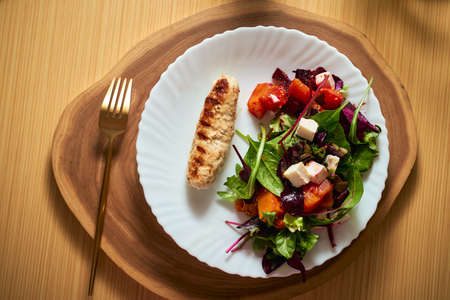 Vegetable salad with beetroot and pumpkin on a white plate with grilled chicken sausage. Very high quality photo. Top view.の写真素材