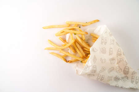 French fries in a paper piece lies on a white background. With copy space. High quality photo