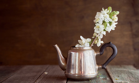 branches with white apple blossoms in an iron teapot on a brown background. high quality photoの写真素材