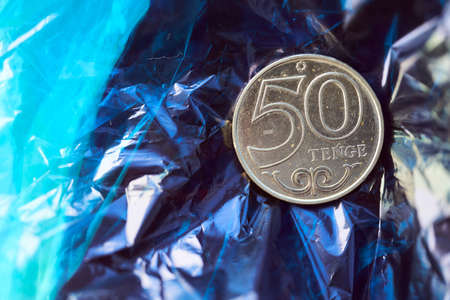 Coin in fifty Kazakhstan tenge on blue film