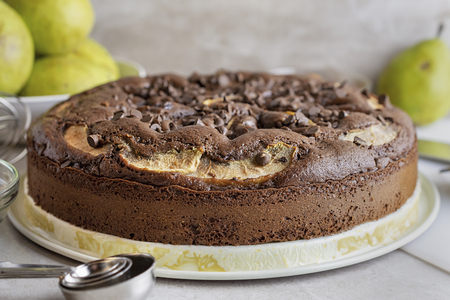 Homemade Chocolate Pear Cake.  Whole cake close up.  Ripened pears in the background.の写真素材