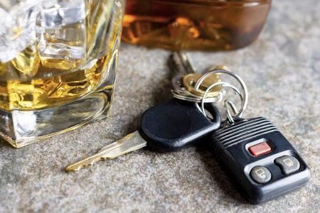Macro view of car keys with glass and bottle of alcohol in the background blurry.  Shot on neutral background.の写真素材