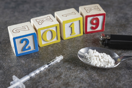 2019 Year of the Drugs?  Syringe with a spoon with white powder (white flour to depict illegal drugs) and a lighter up close.の写真素材