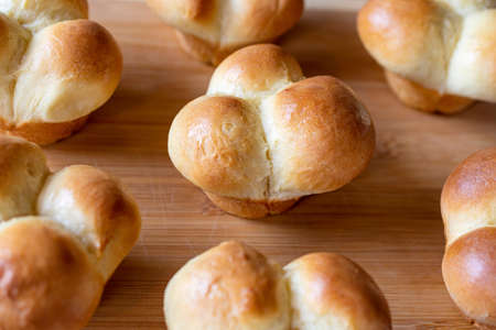Freshly baked clover dinner rolls sit cooling on a bamboo cutting board.の写真素材