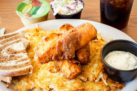 A traditional Wisconsin friday night fish fry from a diner including deep fried cod, coleslaw, marbled rye bread, applesauce, cola, tartar sauce and hashbrowns.の写真素材