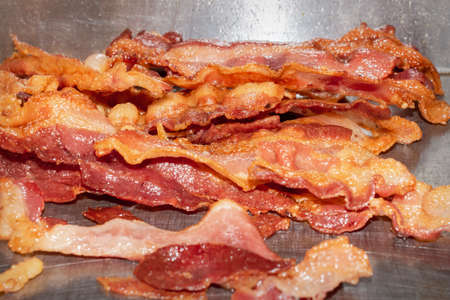 A pile of bacon cooks on a flat grill in a restaurant.の写真素材
