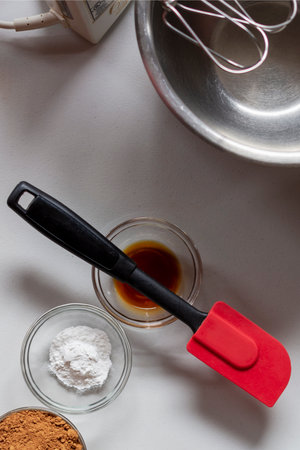 Three small ingredient bowls with a red rubber scrapper.  Mixer with metal bowl at top.