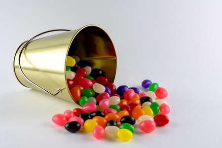 A spilled pail of assorted jelly beans on a white background with copy space.の写真素材