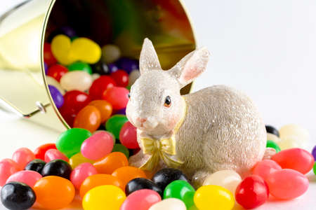An Easter bunny figurine surrounded by assorted jelly beans from spilled pail.  Close up view.の写真素材