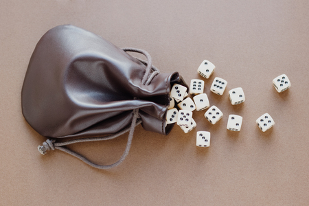 Set of gaming dice rolled out of leather bag on brown background. Concept with copy space for games,...