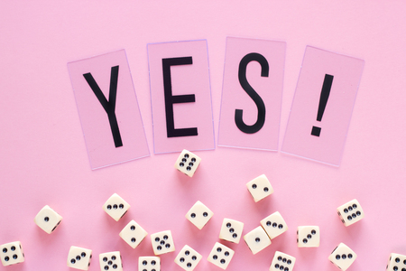 Gaming dice with word YES on pink background. Concept for games, game board, presentation, banners...