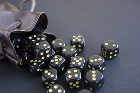 Close-up set of gaming dice rolled out of leather bag on dark background. Concept with copy space for games. Top view. の写真素材