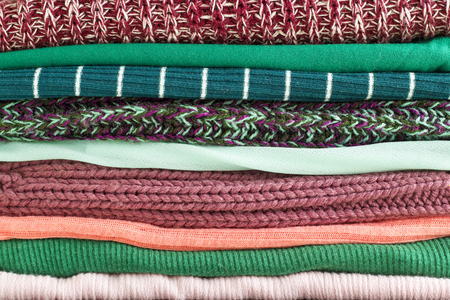 Close-up stack of folded colorful clothes. Background of different cozy clothes. Colorful fabric.の写真素材